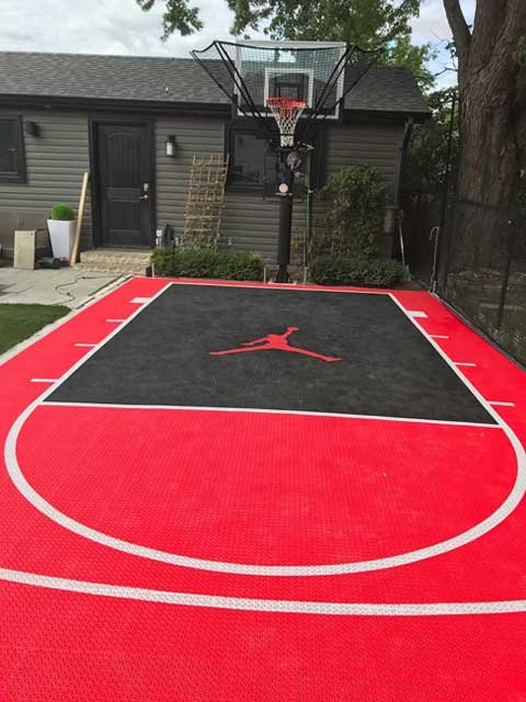 A bold 15' x 38' small backyard basketball court in North York featuring SnapSports® Outdoor Revolution with exclusive ShockTower® Technology. The surface combines vibrant red with a contrasting black key zone and a custom Jumpman logo. Ideal for basketball in compact residential spaces.