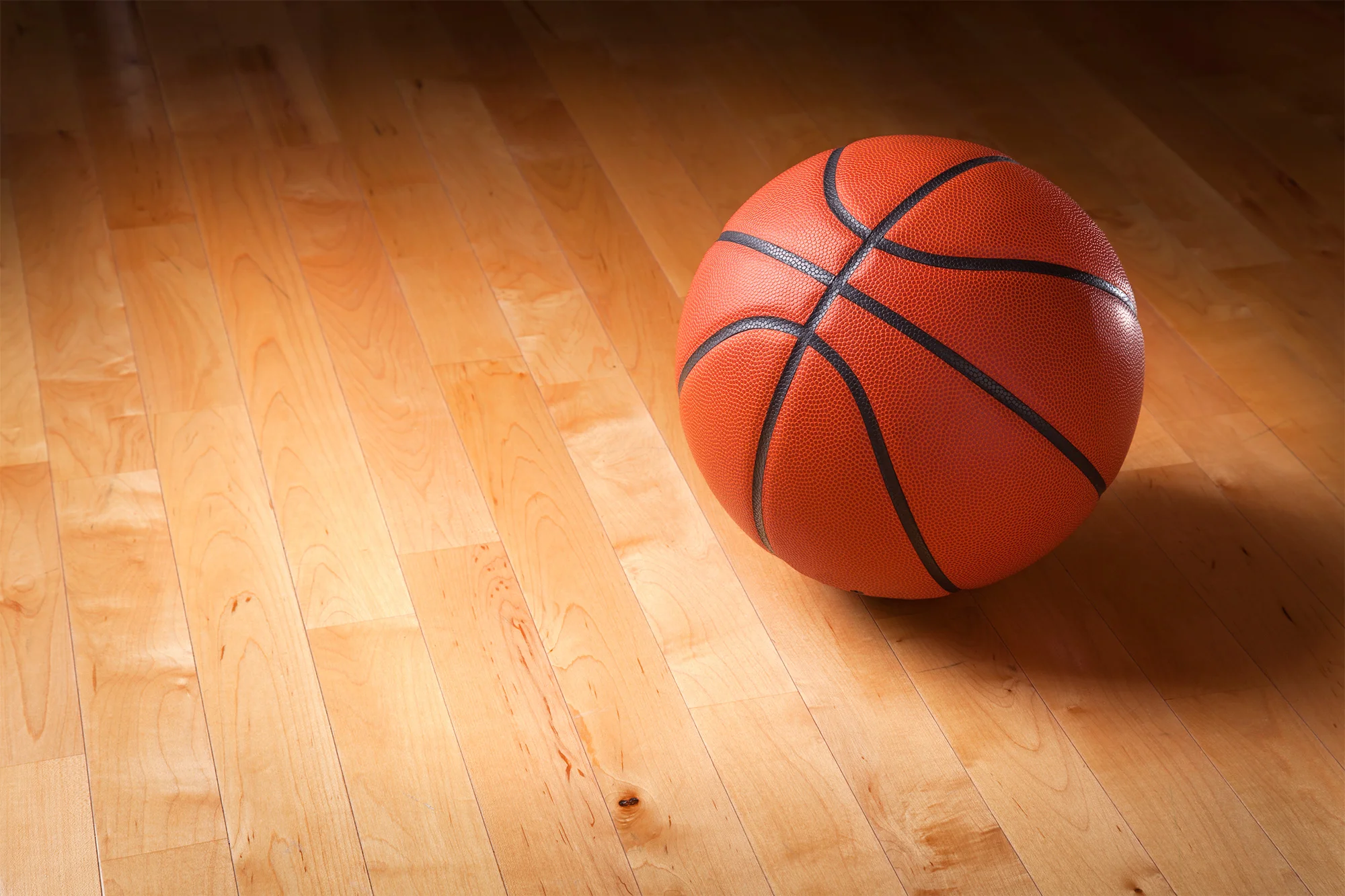 basketball on hardwood court floor with spot light