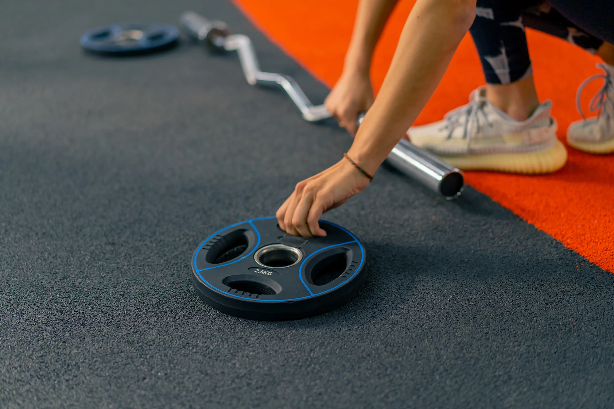 close up female athlete puts weight on the barbell