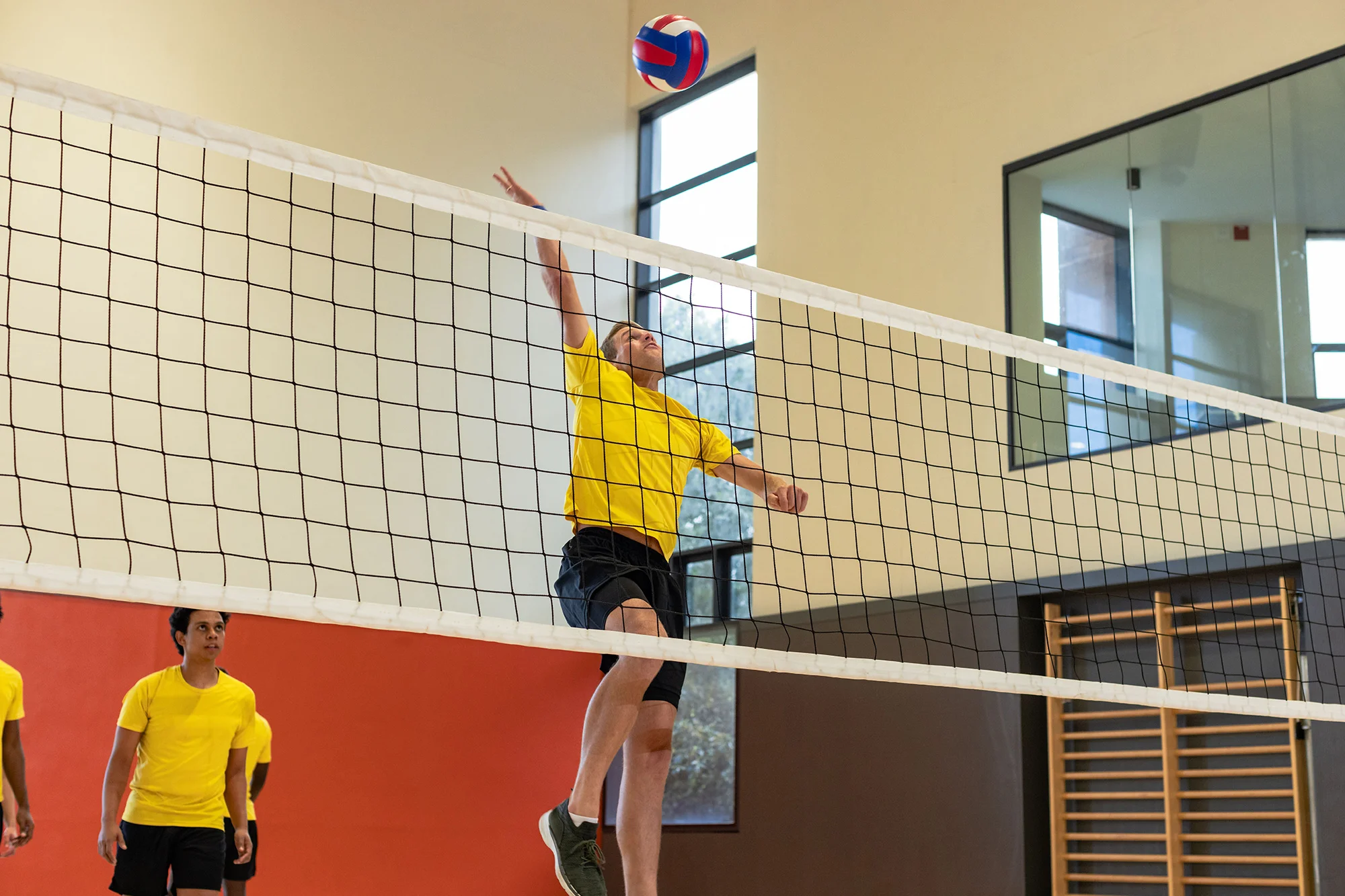 diverse male volleyball athletes jumping and hitti