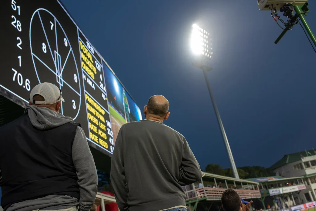 fans looking at cricket scoreboard