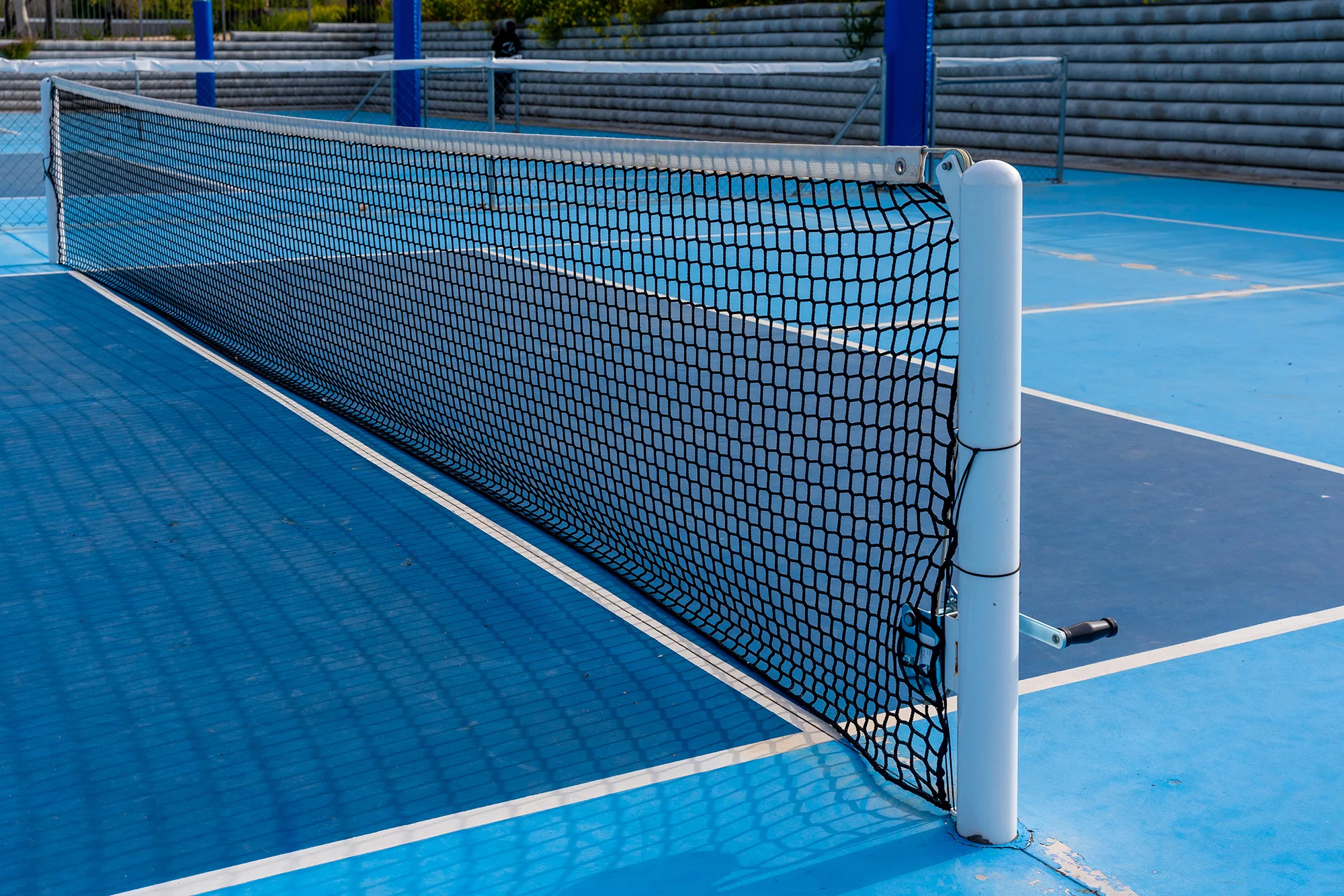 pickleball net in a blue outdoor court banner