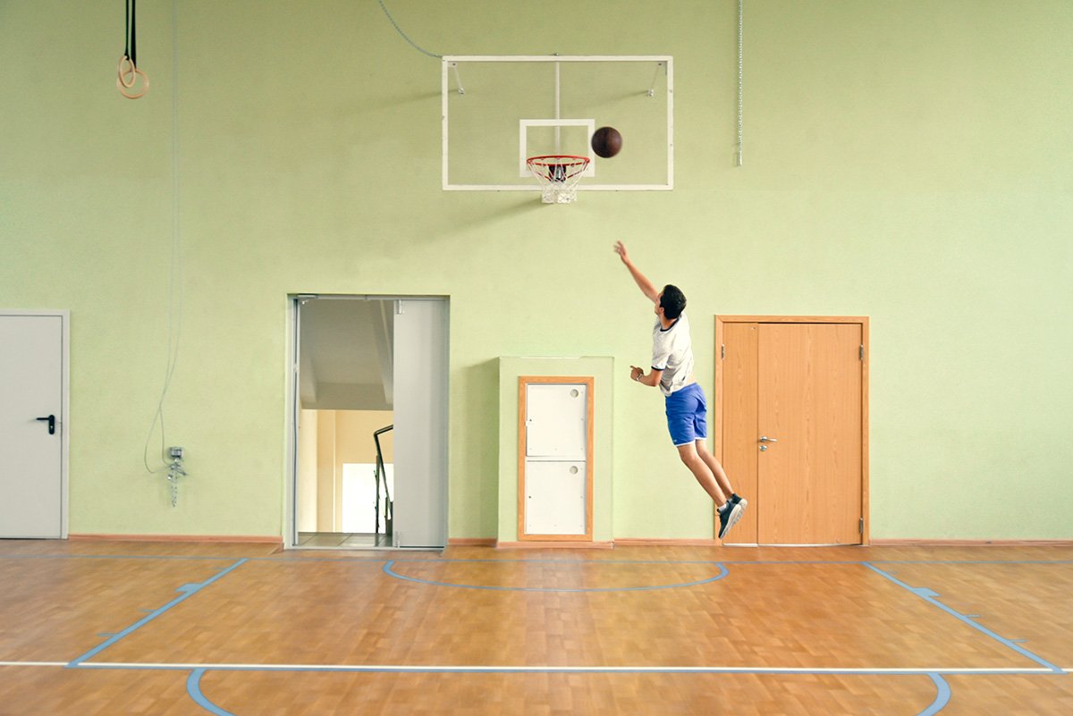 young guy in the gym with a ball playing basketb