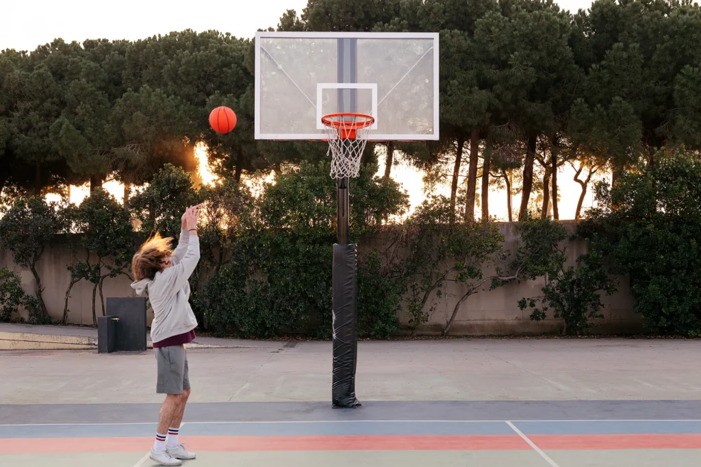 young man shooting baskets in a city park court